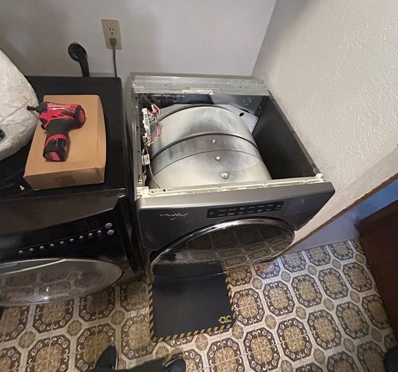 Whirlpool front-load dryer opened up for a drum and belt repair in a west-metro laundry room